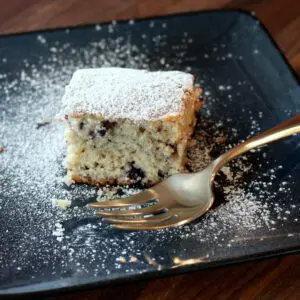 blueberry snack cake with powdered sugar on a plate with fork