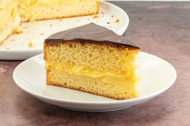 slice of boston cream pie with cake in the background