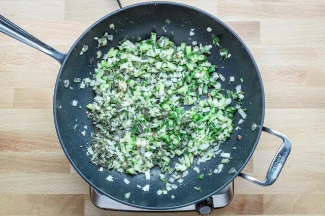 Cooking the onions, celery, and herbs for the sausage stuffing with brioche.