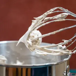 a wire whisk lifted from a bowl of brown sugar meringue