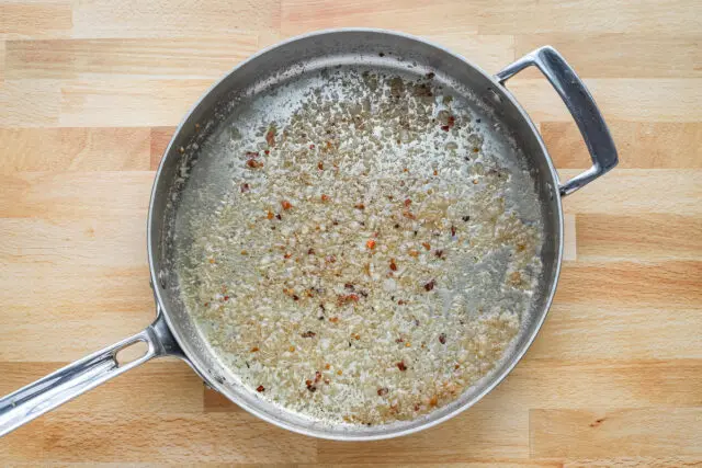 Shallots and garlic are sauteéd in the fat left in the pan, then the pan is glazed with wine and red pepper flakes are added.