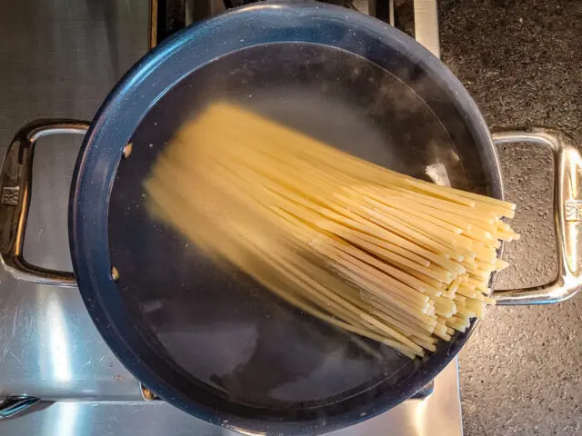 The bucatini is added to the boiling water.