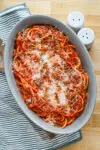 A serving bowl with bucatini all'Amatriciana topped with grated pecorino Romano and extra guanciale.