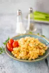 Buffalo chicken mac and cheese on a plate with some parsley and grape tomatoes.