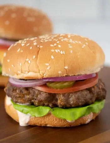 grilled burger with chipotle mayonnaise or aioli on a board with a cheeseburger in the background