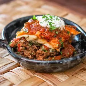 burrito casserole on a plate with garnishes and sour cream