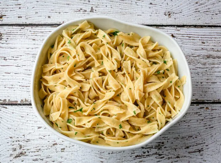 buttered noodles with parsley in a serving bowl