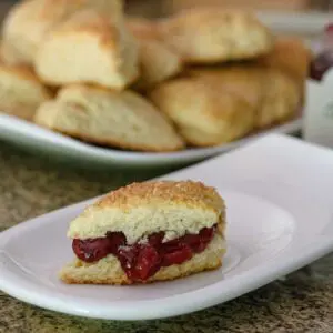 buttermilk scones with one on a plate with cherry jam