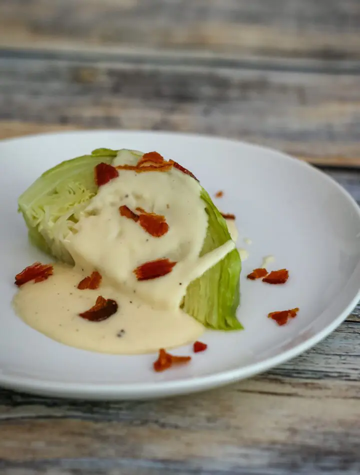 wedge of cabbage on a plate with cheese sauce bacon