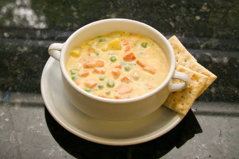 bowl of fresh salmon chowder with peas, carrots, and potatoes