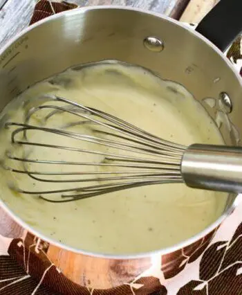 cheese sauce in a copper pan with whisk