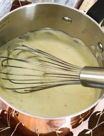 cheese sauce in a copper pan with whisk