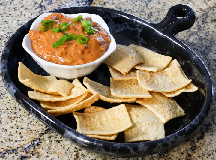 chili cheese dip with sausage on a plate with chips