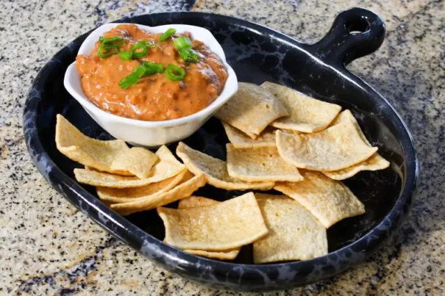 chili cheese dip with sausage on a plate with chips