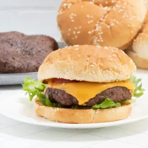 bacon cheeseburger on a plate with lettuce and tomatoes.