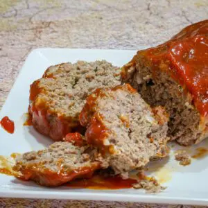 A sliced loaf of tomato soup meatloaf on a platter.