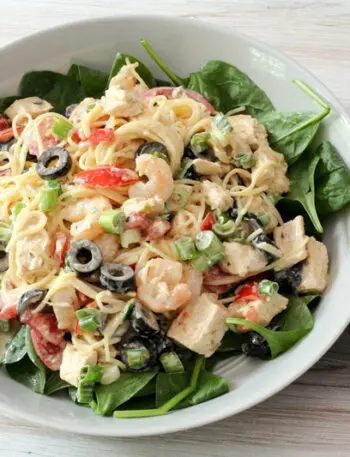 chicken and shrimp pasta salad with angel hair pasta and olives, in a serving dish