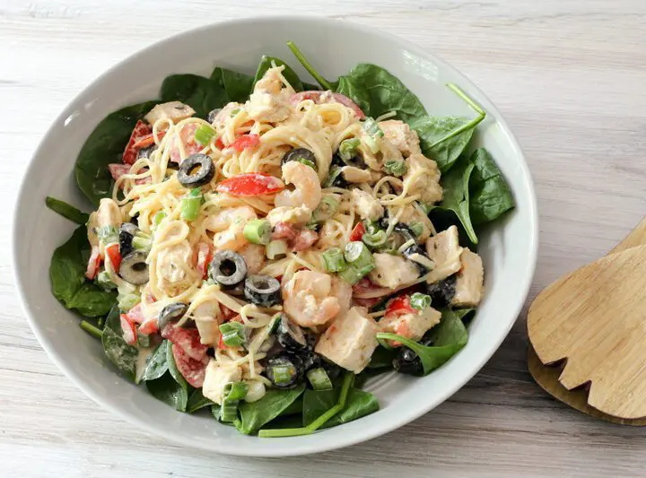 chicken and shrimp pasta salad with angel hair pasta and olives, in a serving dish