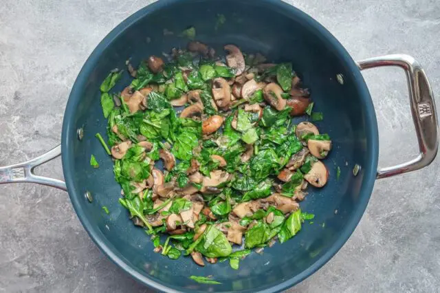 Adding spinach to the skillet for chicken tetrazzini
