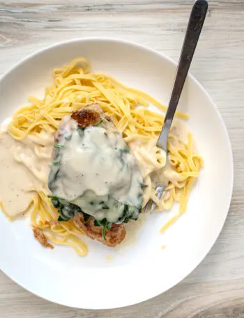 Chicken breasts with a topping of wilted spinach and melted Gruyère cheese on pasta with a creamy white wine and Parmesan cheese sauce.