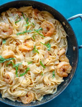 shrimp fettuccine in a skillet with chile crisp and basil garnish