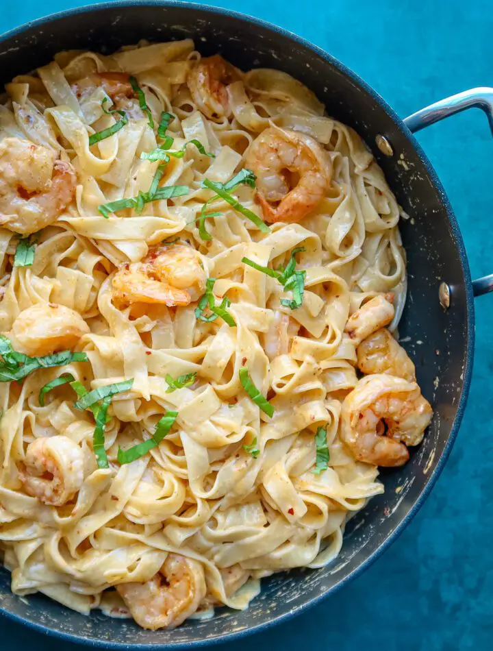 shrimp fettuccine in a skillet with chile crisp and basil garnish