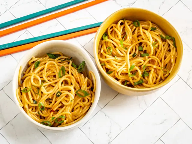 chili garlic noodles in bowls with chopsticks