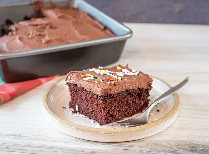 chocolate coconut oil cake slice on a plate with the frosted cake in the background