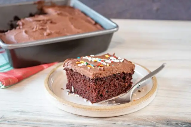 chocolate coconut oil cake slice on a plate with the frosted cake in the background