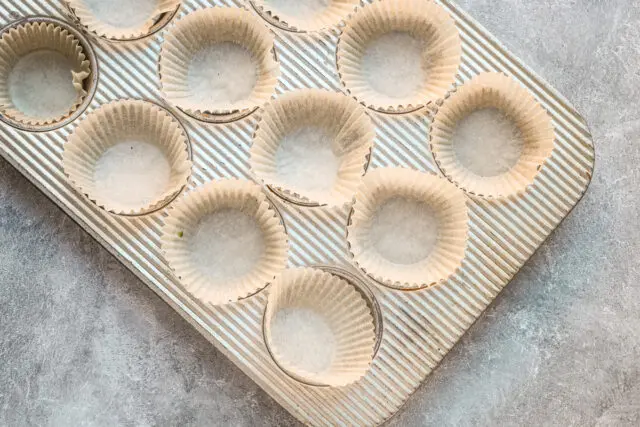 Lining the muffin tins with parchment cupcake papers.