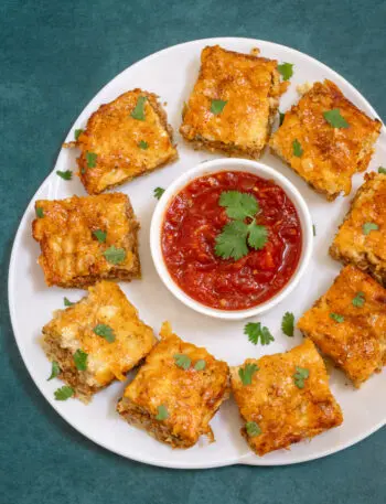 Chorizo sausage quiche squares on a platter with salsa.