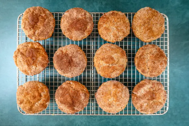 Baked cinnamon muffins on a cooling rack.