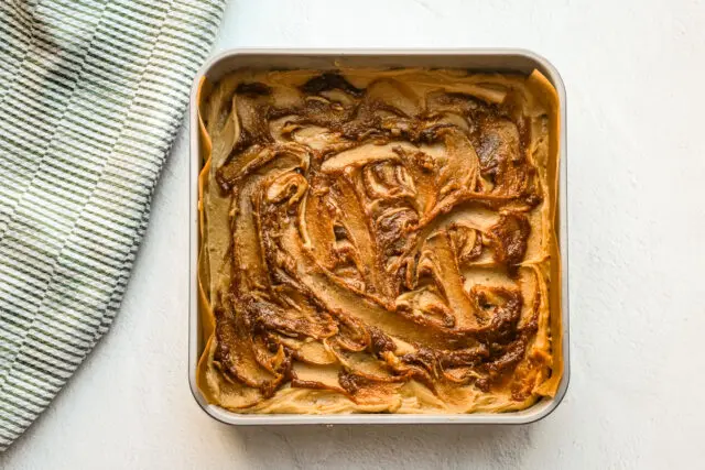 The first layer of batter in the pan with swirls of cinnamon batter.