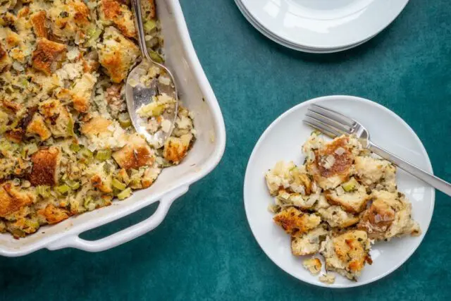 bread stuffing or dressing on a plate with baking dish on the side