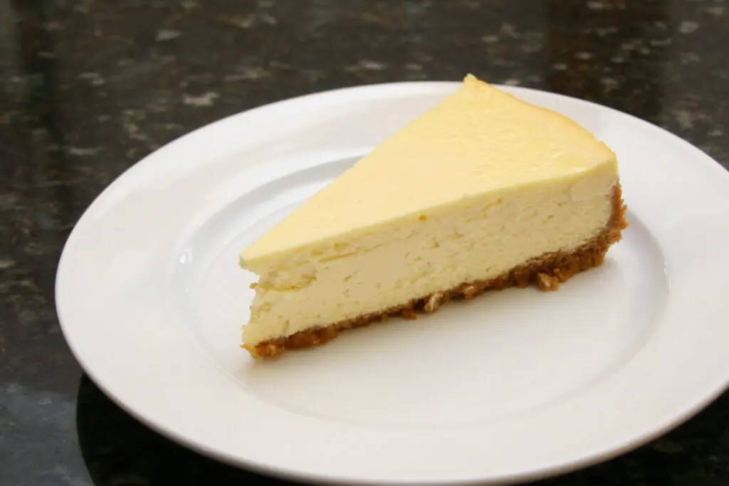 A slice of classic cheesecake with no garnish, on a plate.