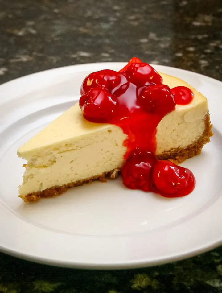 A slice of classic cheesecake with a garnish of cherry pie filling