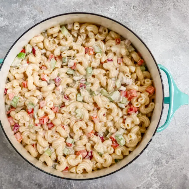 A creamy, flavorful macaroni salad with vegetables and a hit of spice in a Dansk pot for serving.