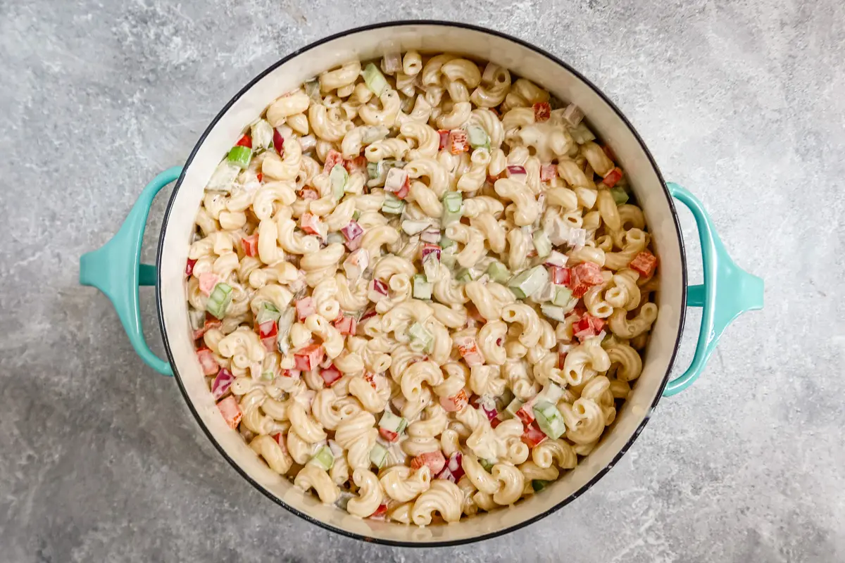 A creamy, flavorful macaroni salad with vegetables and a hit of spice in a Dansk pot for serving.