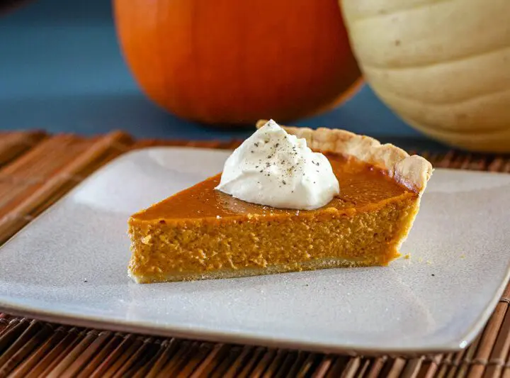 a slice of classic pumpkin pie with whipped cream and a sprinkle of nutmeg