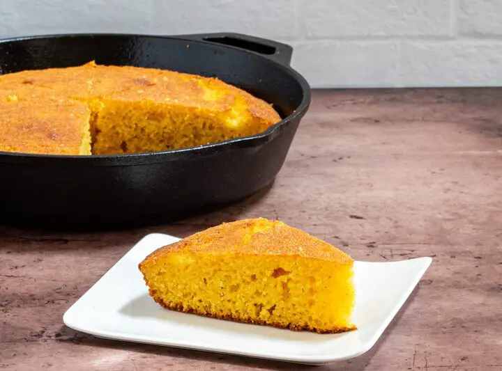 classic american cornbread on a plate with a skillet in the background