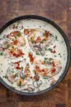 Cooked chicken breasts in a creamy wine sauce garnished with parsley and crispy prosciutto.