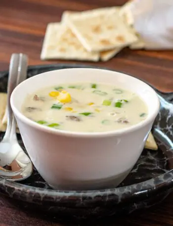 corn and bacon chowder on a luncheon plate with crackers