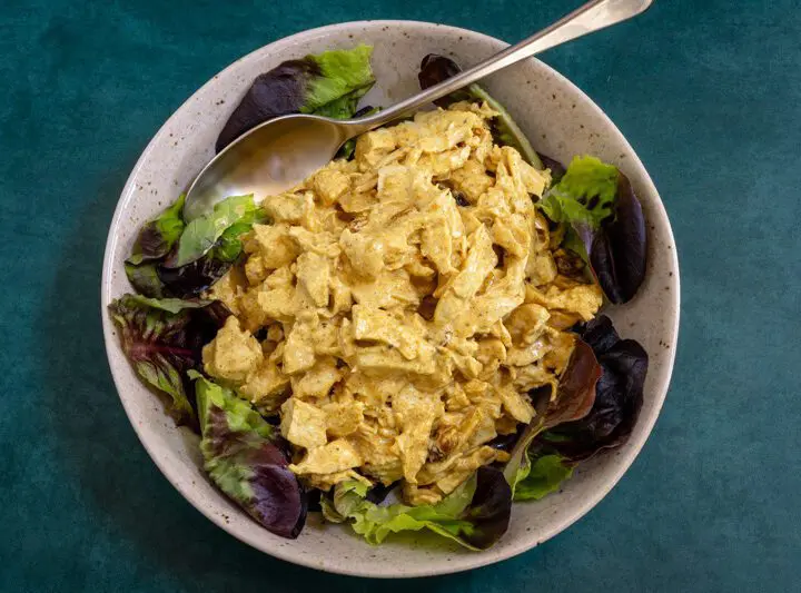 coronation chicken with curry powder in a lettuce-lined bowl