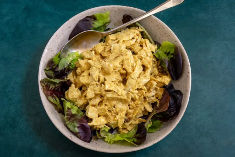 coronation chicken with curry powder in a lettuce-lined bowl