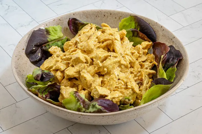 coronation chicken in a bowl on lettuce leaves