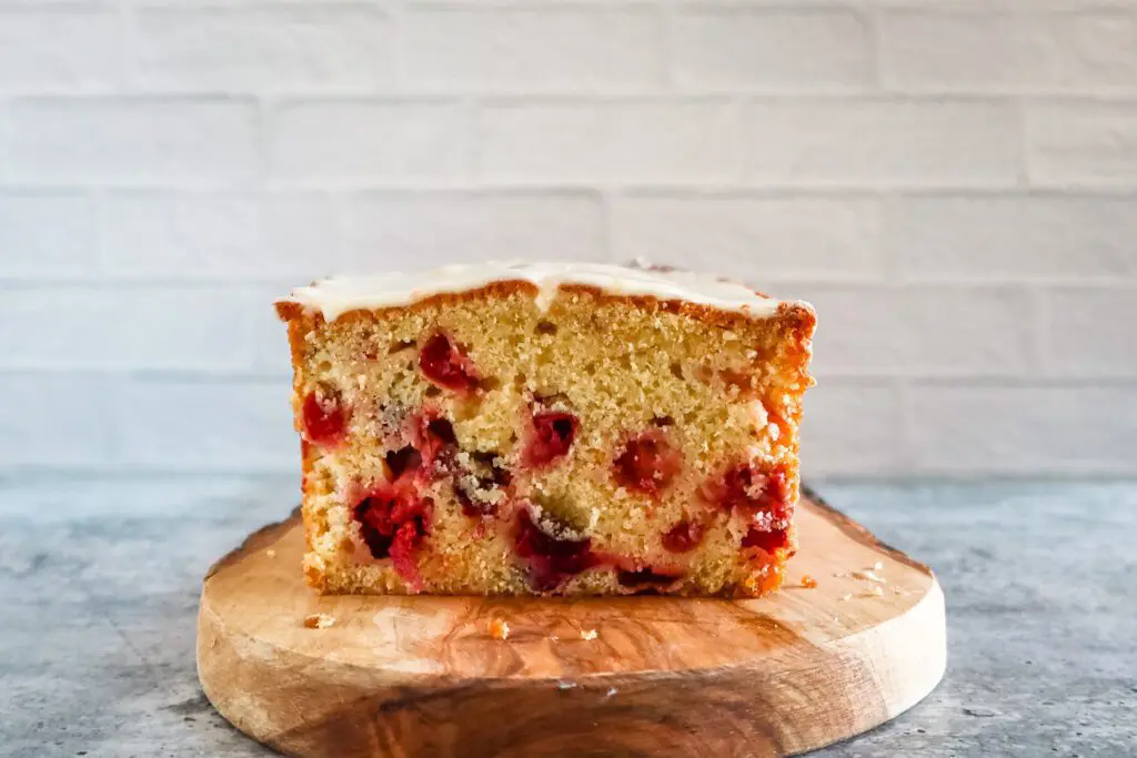 iced cranberry orange bread on a wood board