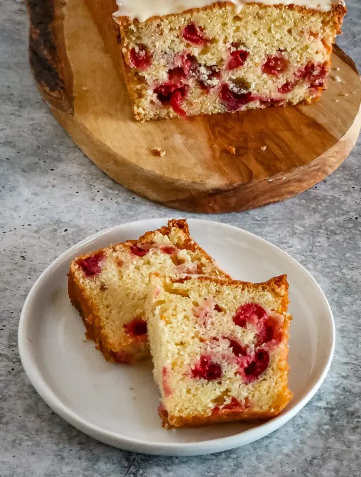 slices of cranberry orange bread on a plate with the loaf in the background