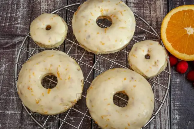 cranberry donuts and a few mini donuts next to a slice of orange and some fresh cranberries