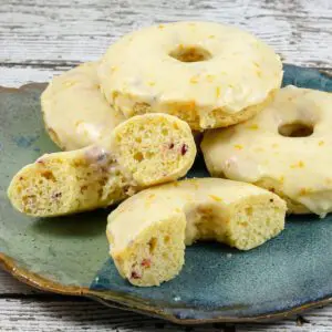 cranberry donuts on a plate with one cut in half