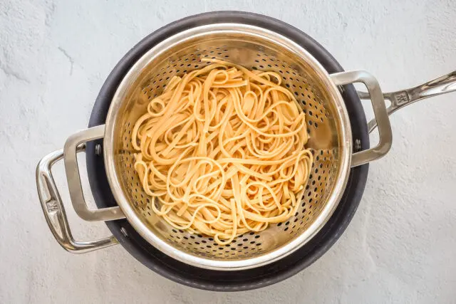 Linguine in a colander for making creamy Cajun chicken pasta.